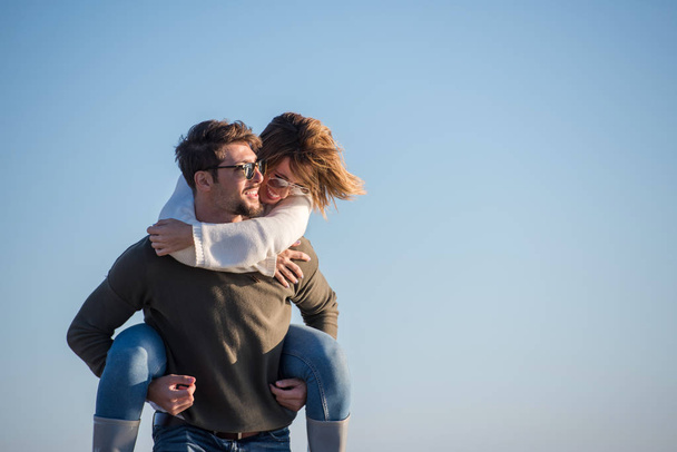 Men Giving Piggy Back Rides to his girlfriend At Sunset By The Sea, autumn time - Foto, Imagen
