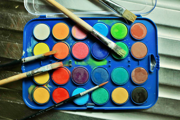 Messy used watercolors with dirty brushes from an art class - Photo, Image