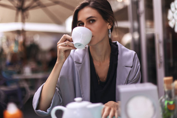 Attractive brunette bussines woman with tail drinking coffee or tea in restaurant. cofee break - Photo, Image