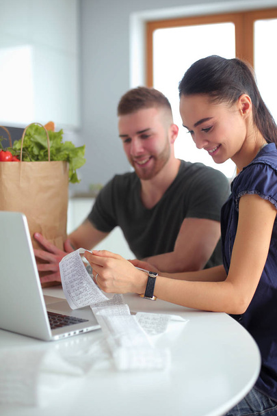 Couple paying their bills with laptop in kitchen at home - Foto, Imagem
