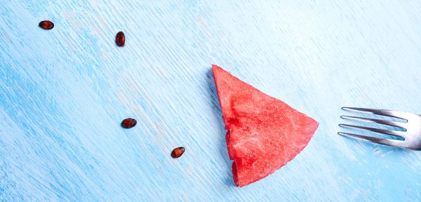 Watermelon slice without skin on blue background. one slice as a arrow or pointer . Top view, flat lay. - Foto, afbeelding