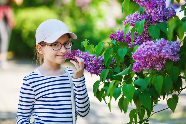 Smiling baby girl and lilac bush in the garden. Selective focus. - Photo, Image