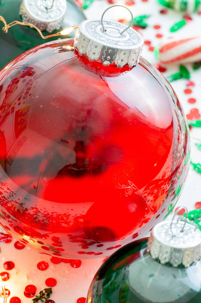 Украшение с красной жидкостью заполнены Рождественский орнамент шар и два зеленых заполненных орнамент шары в окружении красного Have Yourself Веселый Рождественская лента, набор рождественских огней и мяты конфеты
 - Фото, изображение