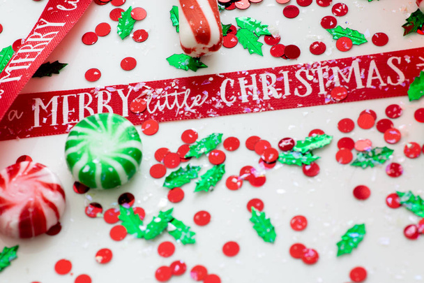 Dekorace s červenou tekutinou naplněné vánoční ozdoba koule a dva zelené plněné ozdoba koule obklopené červenou mají sami A Merry Christmas stuha, sada vánoční osvětlení a peppermint candy - Fotografie, Obrázek