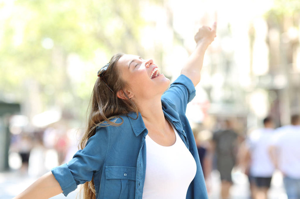 Happy spontaneus woman stretching arms celebrating success in the street - Фото, изображение