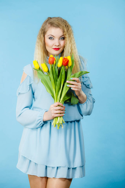International women day, eight march. Beautiful portrait of pretty woman blonde hair with red yellow tulips, fashion make up, elegant dress. Mother day. On blue - Fotografie, Obrázek