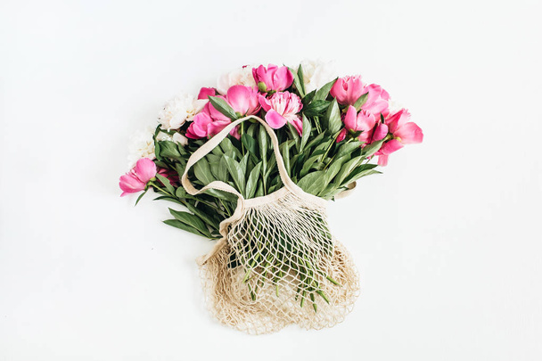 Fiori di peonia rosa e bianchi in sacchetto di corda su sfondo bianco. Layout piatto, vista dall'alto minimale concetto floreale
. - Foto, immagini