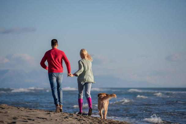 Couple Running On The Beach Holding Their Hands with dog On autmun day - Fotoğraf, Görsel