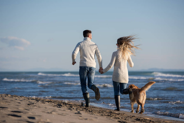Couple Running On The Beach Holding Their Hands with dog On autmun day - Photo, Image
