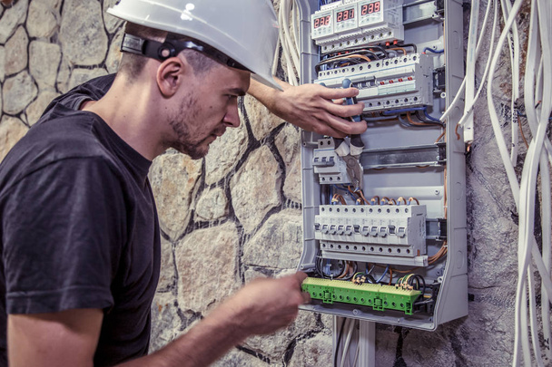 elektryk mężczyzna pracuje w centrali z elektrycznego kabel łączący, łączy sprzęt, narzędzia, pojęcie skomplikowanej pracy, miejsca na tekst - Zdjęcie, obraz