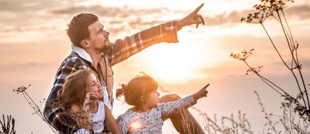 Felice famiglia amorevole, papà giocare con due piccole figlie carine al tramonto seduto su un'alta montagna bella, il concetto di relazioni familiari e di amicizia
 - Foto, immagini