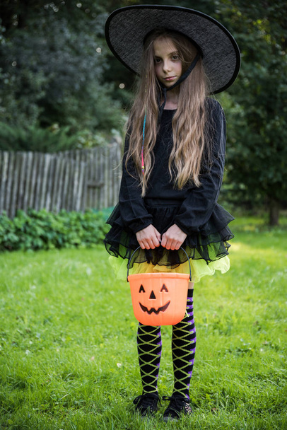 Meisje in heks kostuum, halloween in tuin. - Foto, afbeelding
