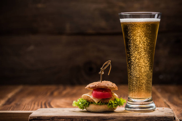 Μίνι βοδινό μπιφτέκι και μπύρα γυαλί, ξύλινη σανίδα. - Φωτογραφία, εικόνα