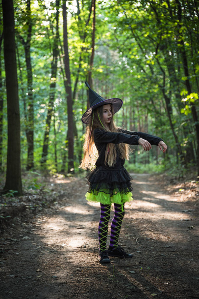 Menina em traje de bruxa na floresta no dia das bruxas
 - Foto, Imagem