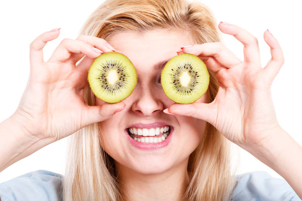 Healthy diet, refreshing food full of vitamins. Woman holding sweet delicious green kiwi fruit, pretending it is eyeglasses. - Fotó, kép