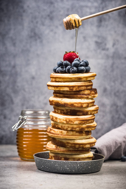 Pancakes stack topped with fruits and maple syrup. - Zdjęcie, obraz
