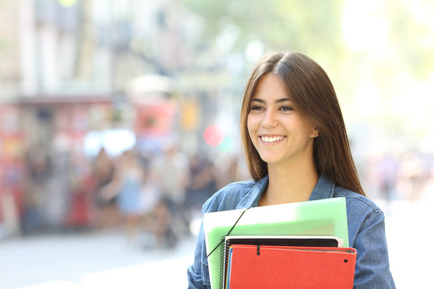 Happy student holding folders walking on the street - Foto, imagen