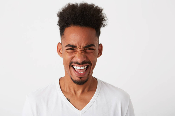 Portrait of cheerful excited african american young man with curly hair wears t shirt feels excited and laughing isolated over white background - Foto, Bild