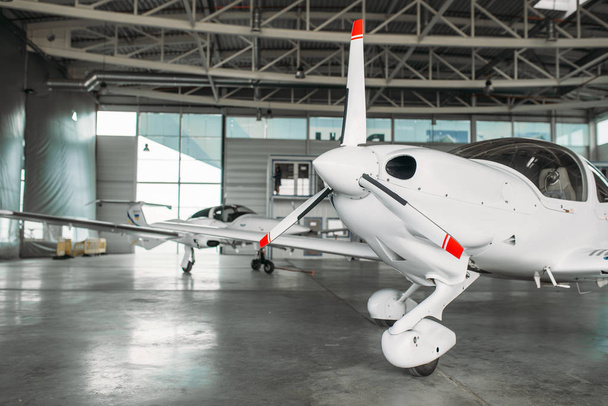Pequeno avião turbo-hélice privado em hangar, avião em inspeção antes do voo. Transporte aéreo, vista frontal no avião turboélice
 - Foto, Imagem