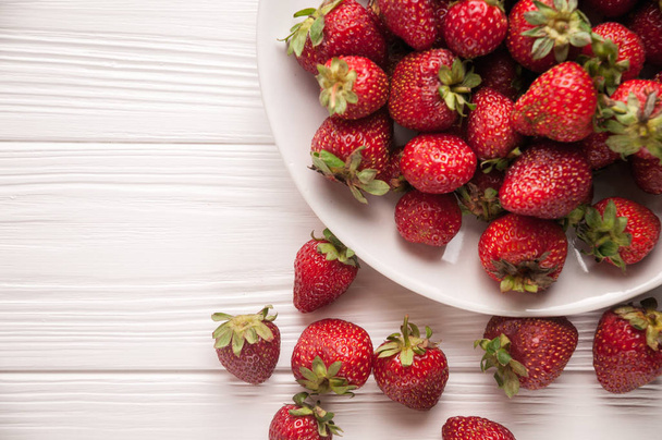 Fresh strawberries in a plate on a white wooden background - Valokuva, kuva