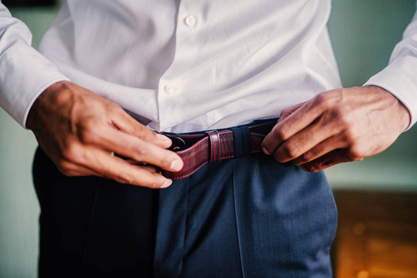 Close up of mans hands putting belt on his pants. - Fotó, kép