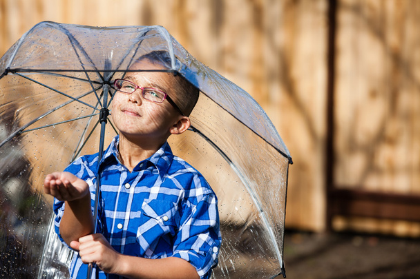 Young boy in a sun shower with umbrella - Fotó, kép
