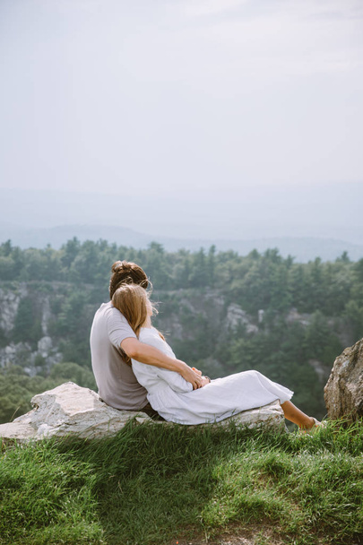Young couple sitting on the edge of mountains with a beautiful view - Photo, Image