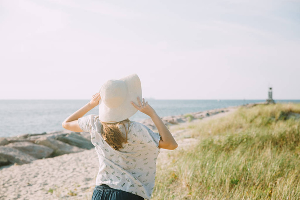 Deniz kıyısına yakın hasır şapka olan kadın - Fotoğraf, Görsel