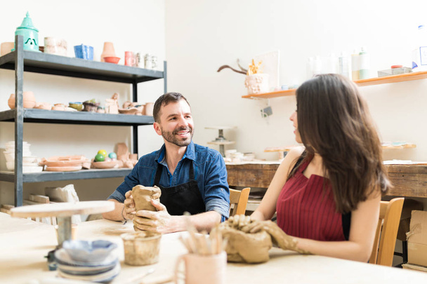 Amour mi-adulte couple regardant les uns les autres tout en faisant des œuvres d'art en classe de poterie
 - Photo, image