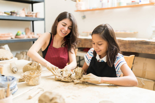Donna e ragazza impastare argilla per fare arte prodotto a tavola in laboratorio di ceramica
 - Foto, immagini