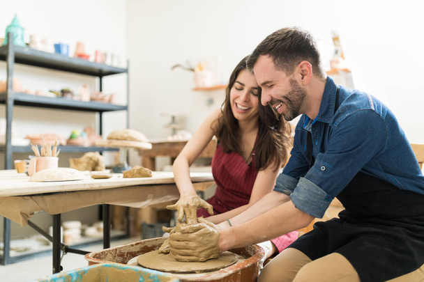 Happy mid adult couple showing their creativity while dating in pottery class - Photo, Image