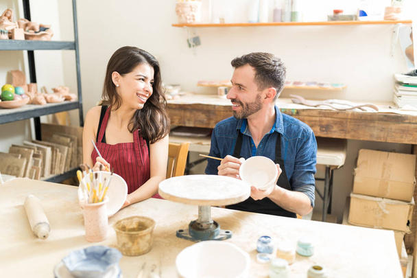 Lächelndes erwachsenes Paar hat Spaß beim Töpfern in Werkstatt - Foto, Bild