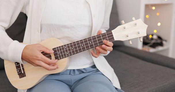 Woman playing on ukulele at home - Foto, afbeelding