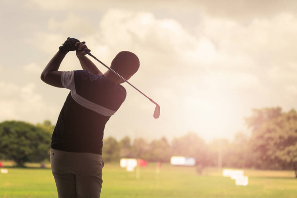 Man hitting golf shot with club on course at evening time. - Photo, Image