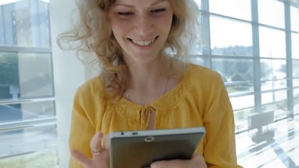 Young beautiful business woman, by the window with a tablet - Materiał filmowy, wideo