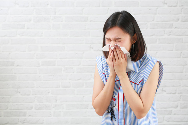 Young woman having sneeze on  background. - Foto, afbeelding