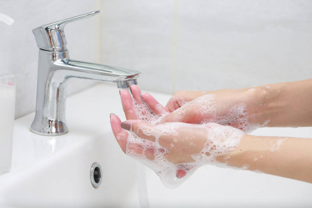 Handen wassen met zeep onder de kraan met water. - Foto, afbeelding