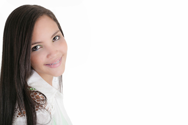 Linda adolescente latina sonriendo con aparatos ortopédicos en un fondo blanco
 - Foto, imagen