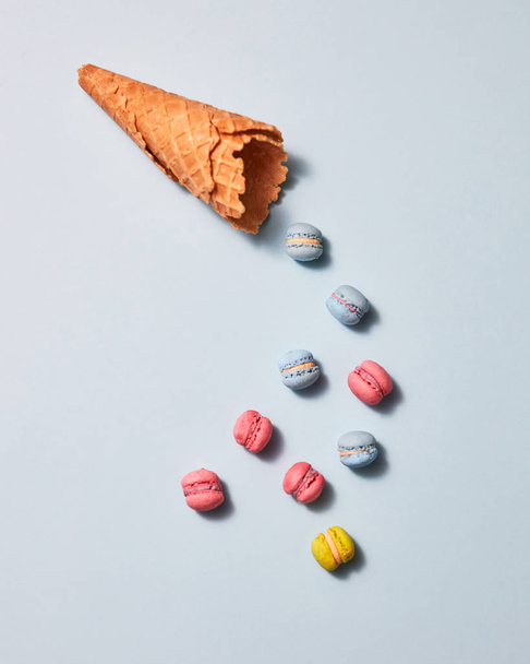 Appetizing waffle cone and tasty macaroons on a gray background with shadows, copy space. Creative food background. Flat lay - Φωτογραφία, εικόνα
