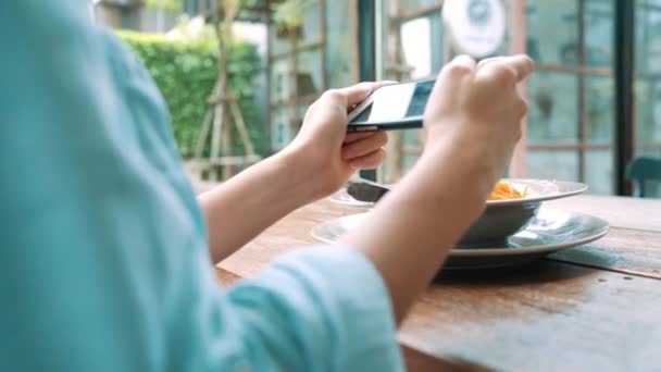Female blogger photographing lunch in restaurant with her phone. A young woman taking photo of spaghetti food on smartphone, photographing meal with mobile camera. - Video