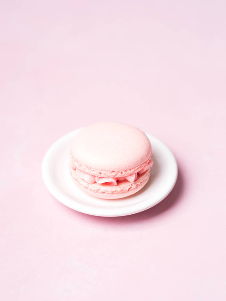 French strawberry macaroon on saucer over pink pastel background - Foto, Imagen