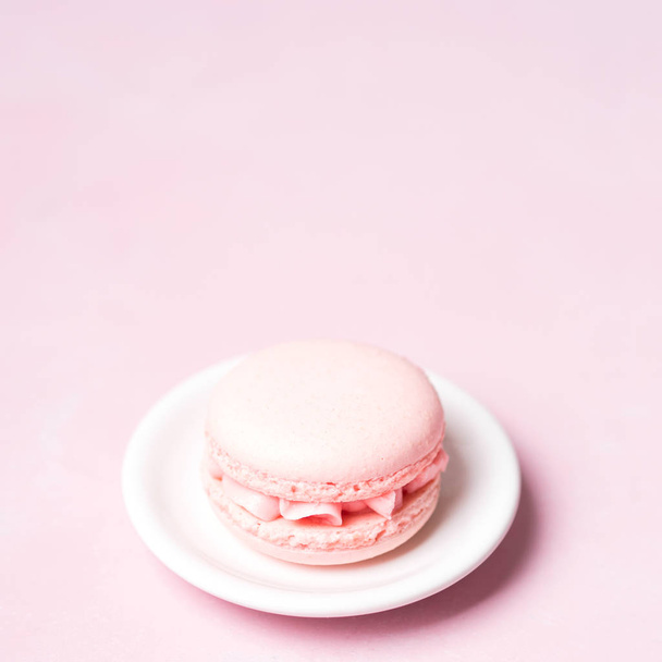 French strawberry macaroon on saucer over pink pastel background - Photo, Image