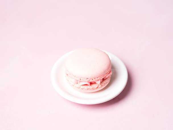 French strawberry macaroon on saucer over pink pastel background - Foto, afbeelding