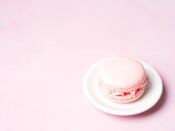 French strawberry macaroon on saucer over pink pastel background - Fotoğraf, Görsel
