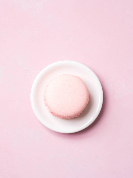 Top view of french strawberry macaroon on saucer over pink pastel background - Photo, Image
