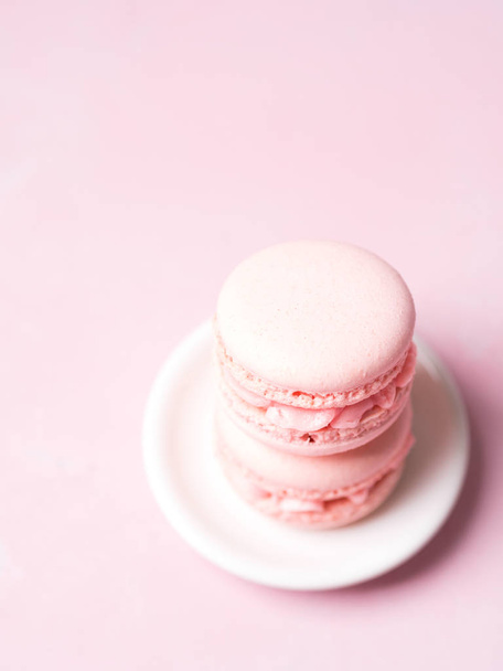 Stack of french strawberry macaroons on saucer over pink pastel background - Foto, Bild