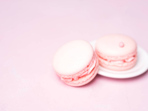 French strawberry macaroons on saucer over pink pastel background - Foto, Imagen