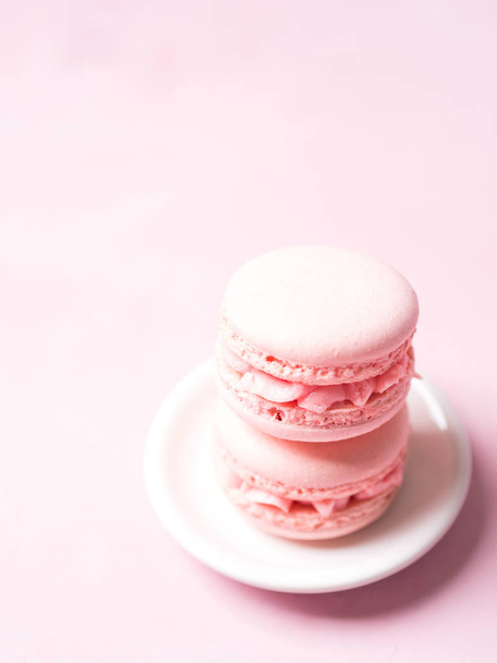 Stack of french strawberry macaroons on saucer over pink pastel background - Fotó, kép