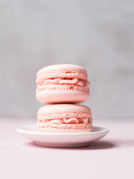 Couple fresh strawberry macaroons on saucer over stone grey background - Foto, Imagen