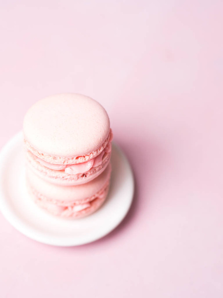 Stack of french strawberry macaroons on saucer over pink pastel background - Foto, immagini